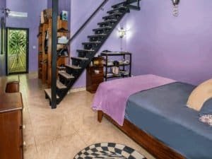 Interior of a bedroom with a bed, staircase, and purple walls in Costa Rica.