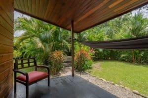 Cozy covered porch with red chair overlooking lush tropical garden.