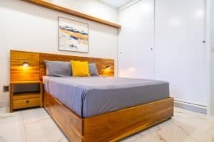 Dominical real estate image of a modern ocean view condo bedroom with wooden bed frame and white til.