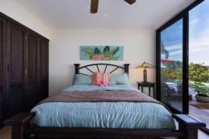 Bedroom with large glass doors overlooking ocean and mountain scenery in Dominical.