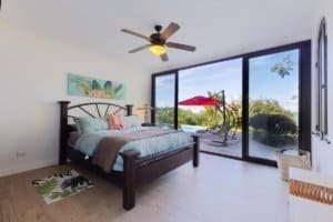 Bright bedroom with large glass doors overlooking lush garden and ocean in Dominical.