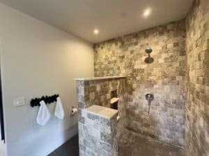 Modern outdoor shower with stone walls and rainfall showerhead.