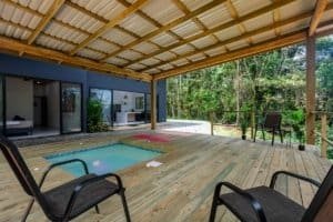 Creekside Costa Rica home with covered patio, pool, and wooden deck in lush forest setting.