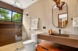 Luxurious bathroom with glass shower, wooden vanity, and modern mirror in jungle retreat.