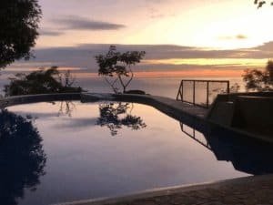 Scenic ocean view sunset over pool with tropical trees in Dominical, Costa Rica.