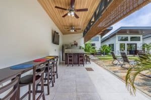Covered patio with bar seating and poolside lounge chairs in a sunny tropical resort.