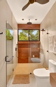 Bright bathroom with walk-in glass shower, large window view of greenery, and modern fixtures.