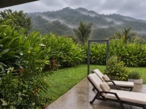 Relaxing outdoor area with lounge chairs, lush greenery, and mountain view.