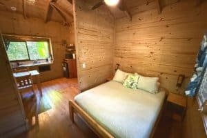 Interior of a rustic wooden bedroom with a large bed and river view.