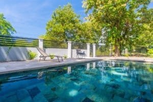 Dominical real estate pool with blue tiles, lounge chairs, and lush trees in tropical setting.
