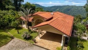 Elegant Costa Rican home with red tile roof and mountain view.