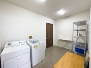 Laundry room with washer, dryer, metal shelving, and ironing board in Costa Rica.
