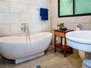 Contemporary bathroom with bathtub, sink, and tropical rainforest view window.