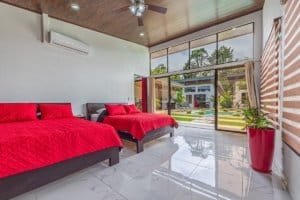 Dominical real estate bedroom with red bedding, large glass doors, and bright natural light.