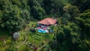 Aerial view of a luxury home with pool in a lush green gated community in Costa Rica.