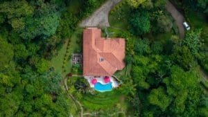 Aerial view of a luxury home with pool, surrounded by lush greenery in Dominical.
