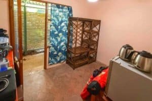 Room with shelves, door to outside, and kitchen appliances in Dominical jungle hotel.
