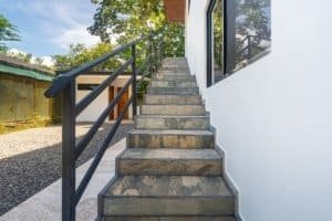 Concrete stairs with metal railing leading to white exterior wall and window.
