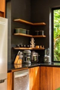 Modern kitchen corner with wooden shelves, coffee station, and blender near window.