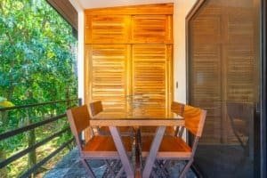 Dominical real estate balcony with wooden table and chairs overlooking lush greenery.