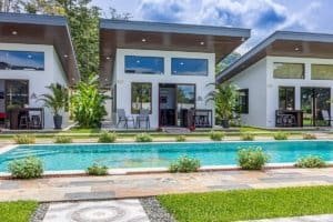 Three modern villas with pool, outdoor seating and tropical plants.