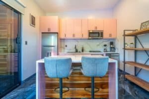 Ocean view condo kitchen with island and two stools, modern cabinets.