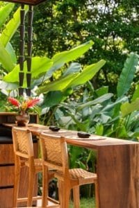 Outdoor wooden counter with chairs amid lush tropical plants in Costa Rica.
