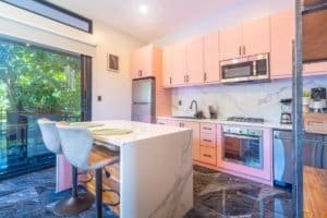 Ocean view condo kitchen with pink cabinetry and marble island.