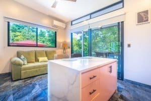 Ocean view condo with modern kitchen island and greenery outside.