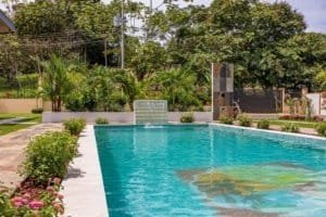 Spacious turquoise pool with surrounding tropical landscaping.