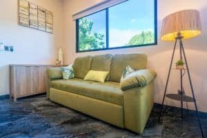Ocean view condo living room with green sofa and floor lamp.