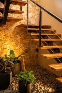Modern staircase with wooden steps and stone wall in a cozy indoor space.