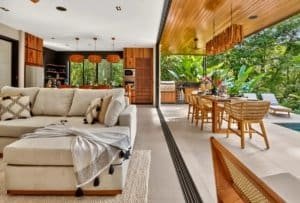 Luxurious tropical living room with open-air dining and lush jungle backdrop.