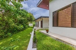 Dominical real estate: manicured lawn, modern villa exterior with large window and surrounding green.