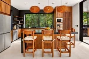 Modern kitchen in a jungle villa with wooden island and seating area.