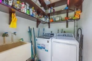 Laundry room with washing machine and dryer, cleaning supplies on shelves.