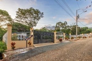 Gated driveway to a residential property in Dominical, Costa Rica with a gravel road and surrounding.