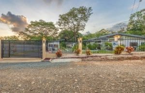 Gated residential property in Dominical with modern fence, tropical landscaping, and a for sale sign.
