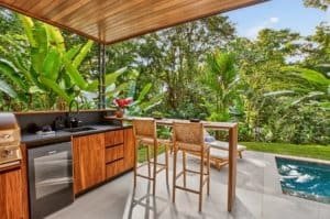Outdoor jungle view kitchen with bar seating and pool in Costa Rica.