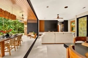 Open-concept living area with seating, large windows, and tropical outdoor patio.