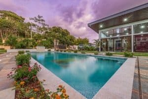 Luxurious modern house with large pool and garden at sunset.