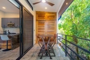 Balcony with table and chairs overlooking lush tropical trees.