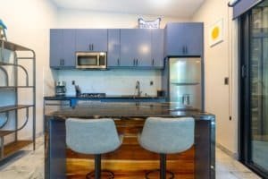 Two blue kitchen cabinets with marble countertops and island seating.