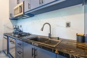 Modern kitchen with marble backsplash and oak cabinets, stainless appliances.