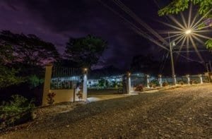 Night view of a gated Costa Rica property entrance with streetlight and landscaping.