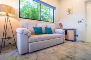 Bright living room with beige sofa and blue cushions near large window.