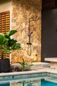 Dominical real estate jungle home with stone wall and outdoor shower.