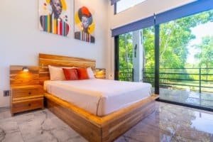 Ocean view bedroom with wood bed and balcony in Costa Rica condo.