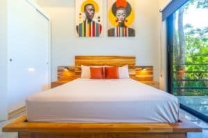 Dominical Costa Rica condo bedroom with wooden bed frame and colorful wall art.