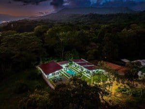 Dominical real estate property with multiple villas and illuminated pool at night.